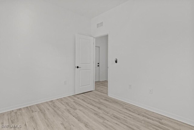 spare room featuring light wood-style flooring, visible vents, and baseboards