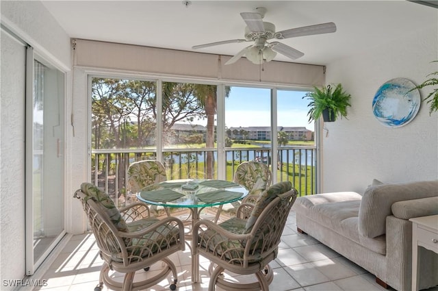 sunroom / solarium featuring a ceiling fan and a water view