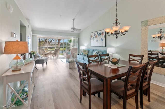 dining space with light wood finished floors, ceiling fan with notable chandelier, and vaulted ceiling