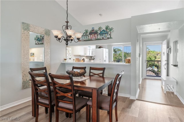 dining room with baseboards, light wood-style floors, and an inviting chandelier