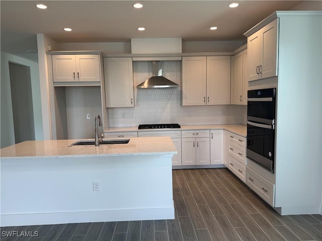 kitchen with a sink, wall chimney range hood, wood tiled floor, black appliances, and tasteful backsplash