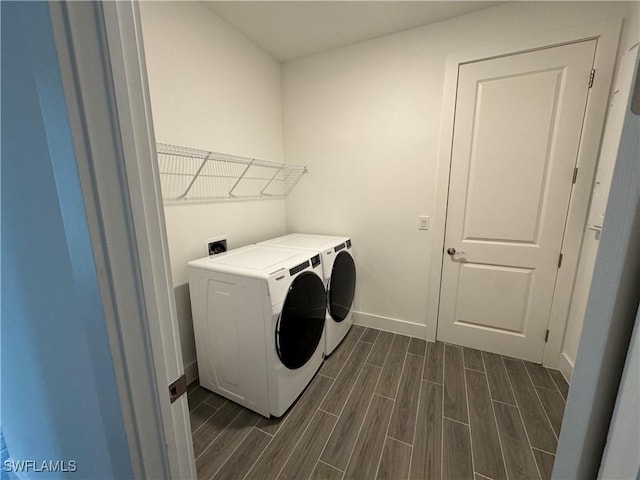 laundry area featuring wood tiled floor, laundry area, washer and clothes dryer, and baseboards