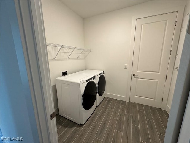 clothes washing area featuring baseboards, dark wood-style flooring, washer and clothes dryer, and laundry area