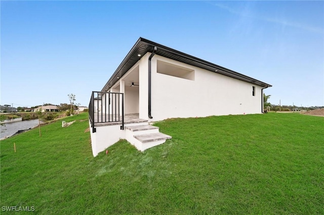 back of house with a lawn and stucco siding