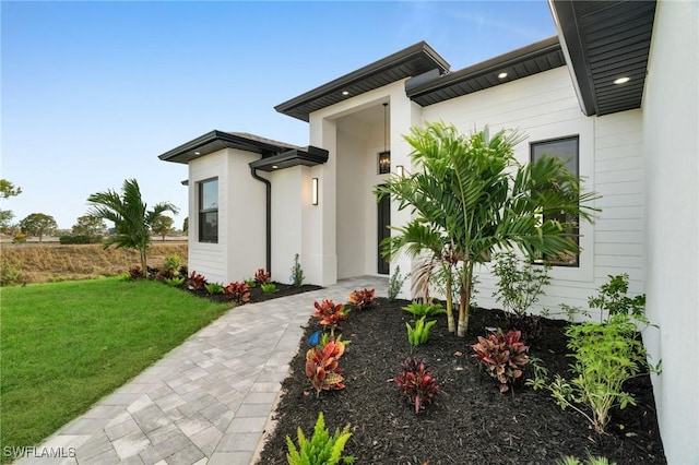 doorway to property with a lawn and stucco siding