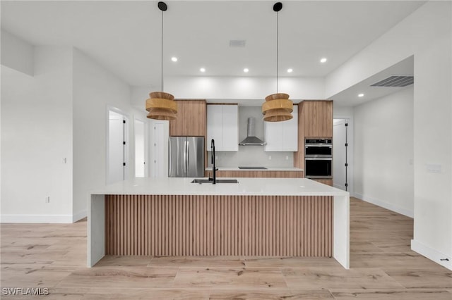 kitchen with stainless steel appliances, light countertops, white cabinets, wall chimney range hood, and modern cabinets