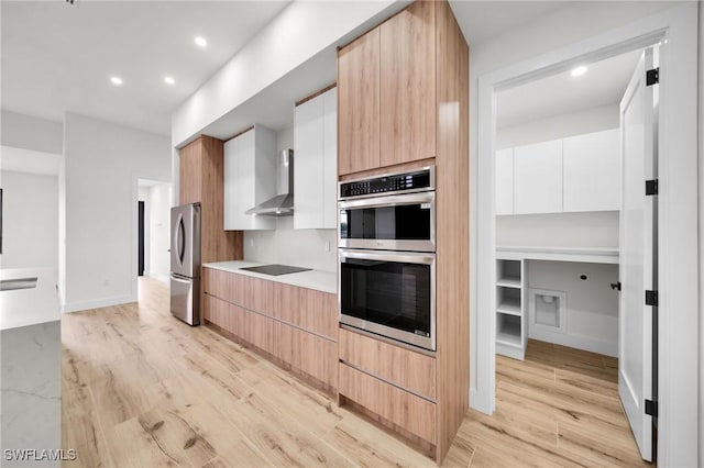 kitchen with light wood-style flooring, appliances with stainless steel finishes, white cabinets, modern cabinets, and wall chimney exhaust hood