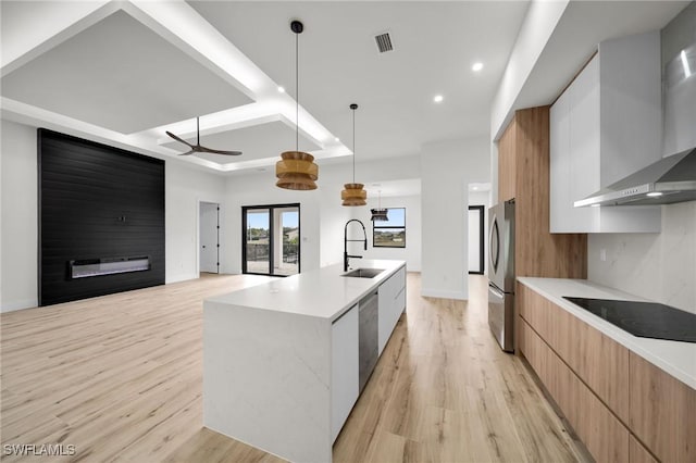 kitchen with a large island, hanging light fixtures, appliances with stainless steel finishes, modern cabinets, and wall chimney exhaust hood