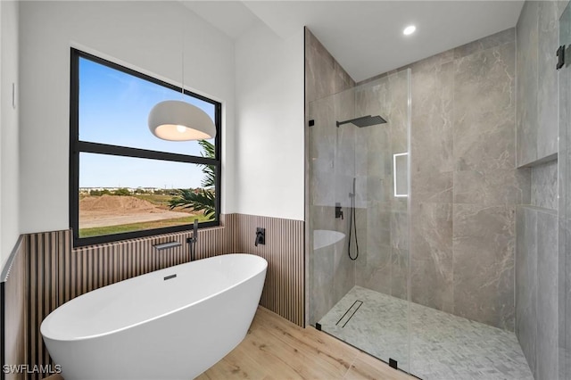 bathroom featuring recessed lighting, a wainscoted wall, wood finished floors, a soaking tub, and walk in shower