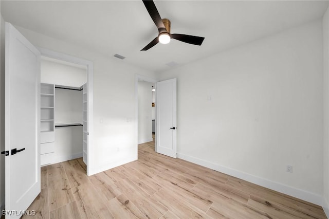 unfurnished bedroom with a closet, visible vents, a spacious closet, light wood-type flooring, and baseboards