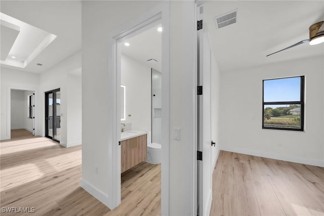 corridor featuring light wood-style floors, baseboards, visible vents, and recessed lighting