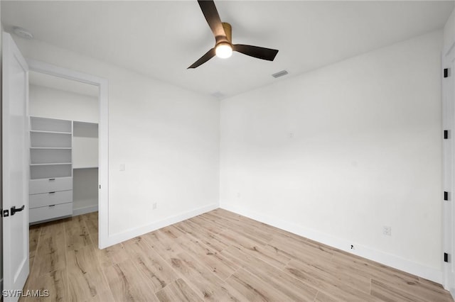 unfurnished bedroom with visible vents, baseboards, a spacious closet, a closet, and light wood finished floors