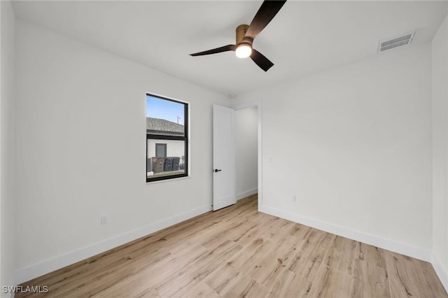 spare room with ceiling fan, light wood-type flooring, visible vents, and baseboards