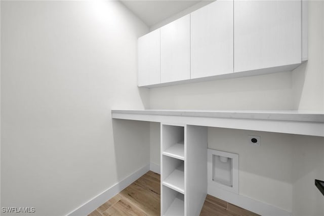 washroom featuring light wood-type flooring, cabinet space, hookup for an electric dryer, and baseboards