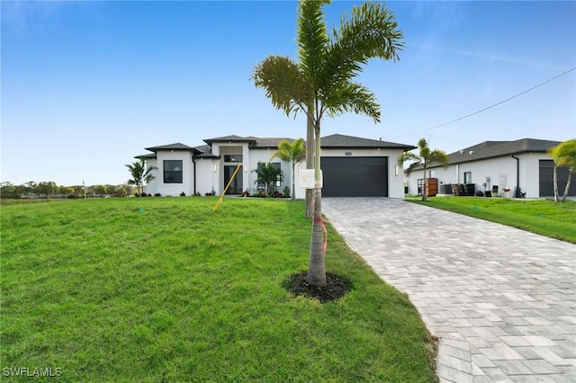 prairie-style house with decorative driveway, an attached garage, and a front yard