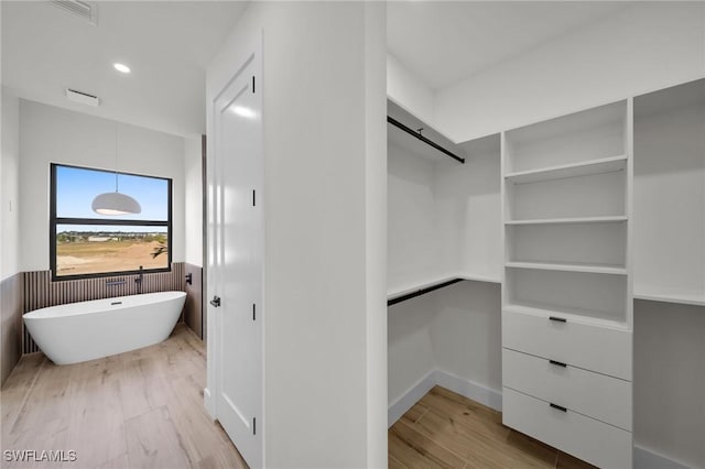 spacious closet featuring visible vents, light wood-style flooring, and a barn door