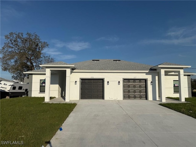 prairie-style house featuring stucco siding, a shingled roof, concrete driveway, a front yard, and a garage