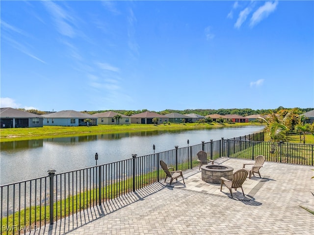 view of patio featuring a residential view, a water view, an outdoor fire pit, and fence