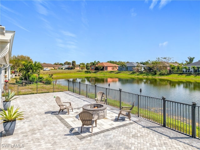 view of patio featuring a water view, an outdoor fire pit, and fence