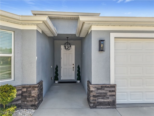 entrance to property featuring stone siding, an attached garage, and stucco siding