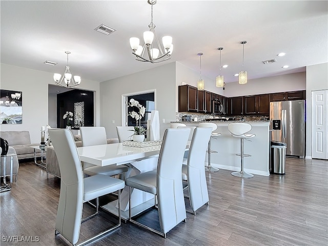 dining room featuring visible vents, a notable chandelier, and wood finished floors