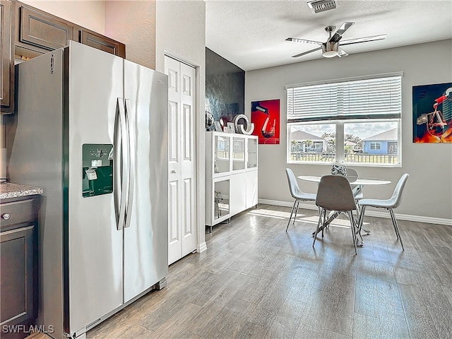 kitchen featuring dark brown cabinetry, light wood-style floors, a textured ceiling, and stainless steel fridge with ice dispenser