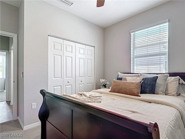 bedroom featuring ceiling fan, light carpet, visible vents, baseboards, and a closet