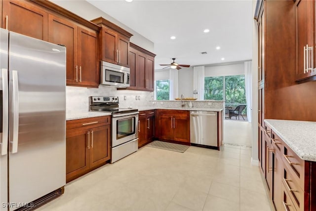 kitchen featuring light stone counters, brown cabinets, stainless steel appliances, backsplash, and a sink