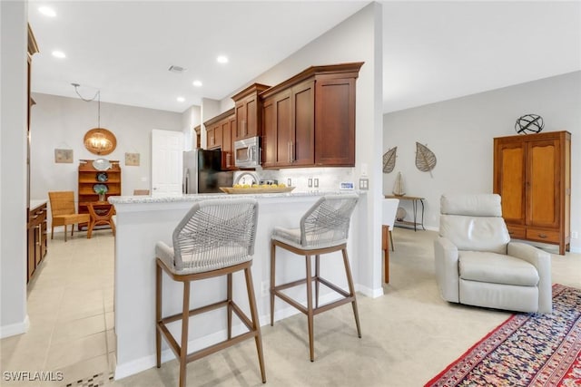 kitchen featuring pendant lighting, backsplash, appliances with stainless steel finishes, open floor plan, and a kitchen breakfast bar