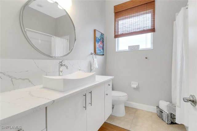 bathroom with tasteful backsplash, toilet, vanity, baseboards, and tile patterned floors