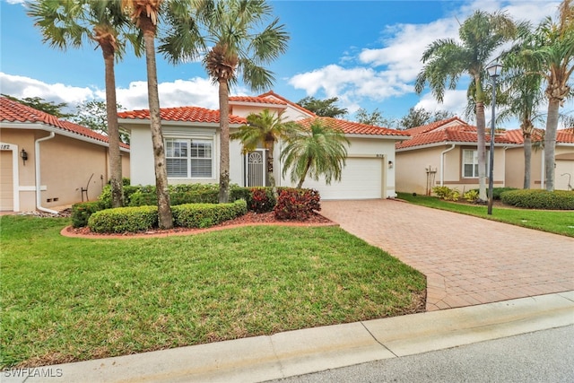 mediterranean / spanish-style house featuring a garage, a front yard, decorative driveway, and a tile roof