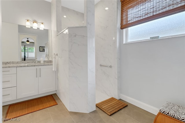 bathroom with tile patterned flooring, a marble finish shower, vanity, and a healthy amount of sunlight