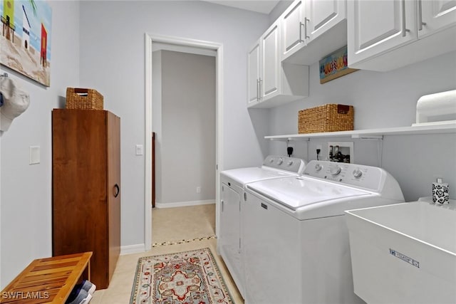 clothes washing area featuring light tile patterned floors, cabinet space, washing machine and dryer, a sink, and baseboards