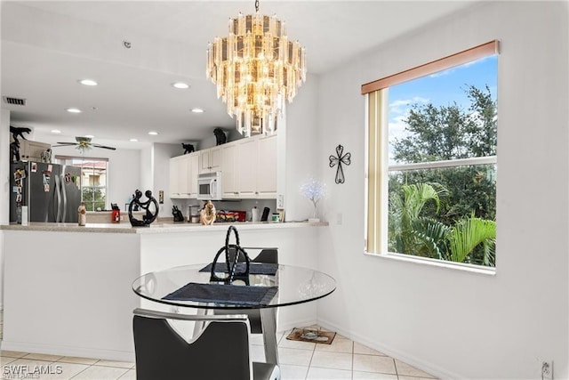 kitchen featuring decorative light fixtures, light countertops, white microwave, freestanding refrigerator, and white cabinetry