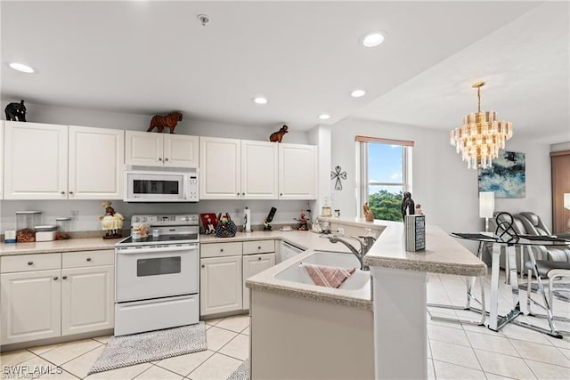 kitchen featuring pendant lighting, light tile patterned floors, light countertops, white cabinetry, and white appliances