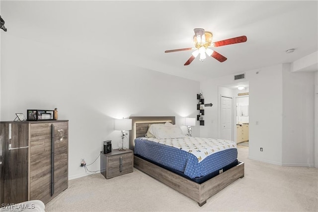 carpeted bedroom featuring a ceiling fan, visible vents, baseboards, and ensuite bathroom