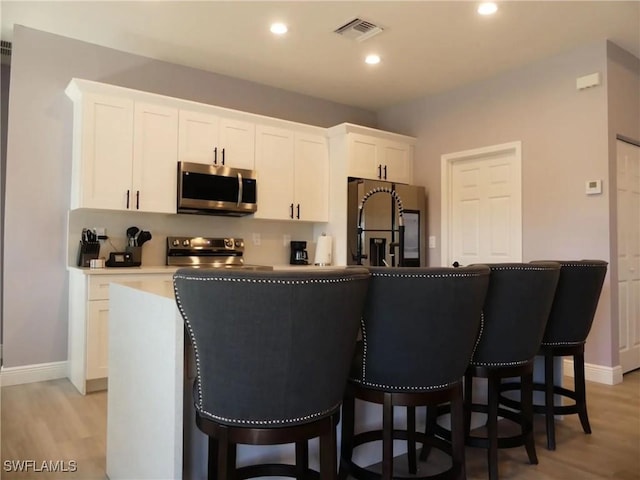 kitchen with a center island, light countertops, visible vents, appliances with stainless steel finishes, and white cabinets