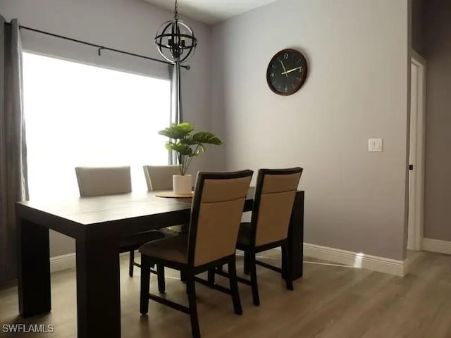 dining room with a notable chandelier, baseboards, and wood finished floors