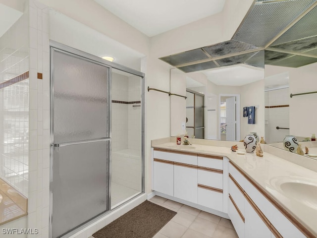 full bath featuring double vanity, a stall shower, a sink, and tile patterned floors