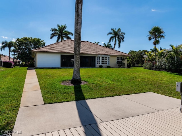 view of front of home with a tiled roof, a front yard, and stucco siding