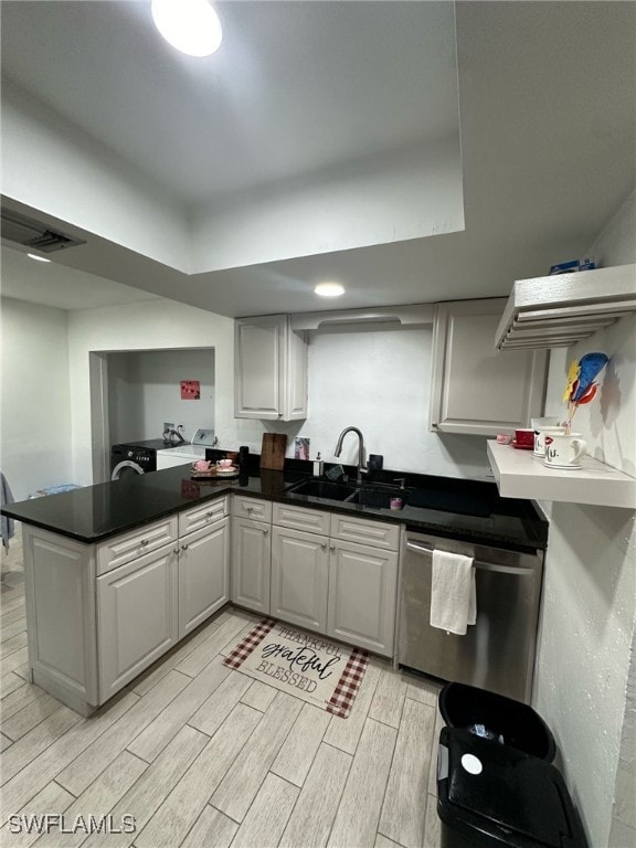 kitchen featuring dark countertops, stainless steel dishwasher, wood tiled floor, and a sink