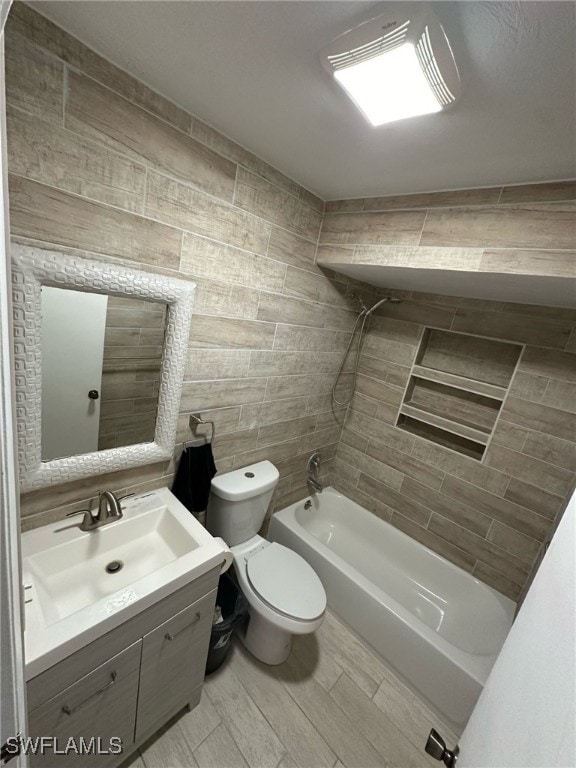 bathroom with toilet, shower / bath combination, wood finished floors, vanity, and tile walls