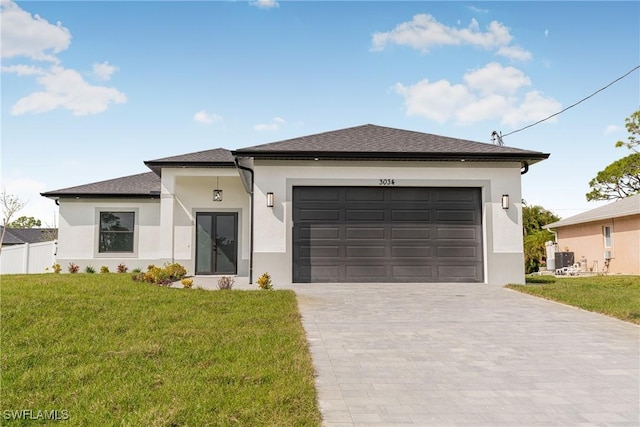 prairie-style house with a garage, fence, decorative driveway, stucco siding, and a front yard