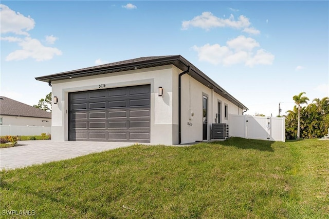 garage featuring decorative driveway, central AC, fence, and a gate