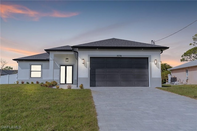 view of front of house with driveway, roof with shingles, an attached garage, a front yard, and stucco siding