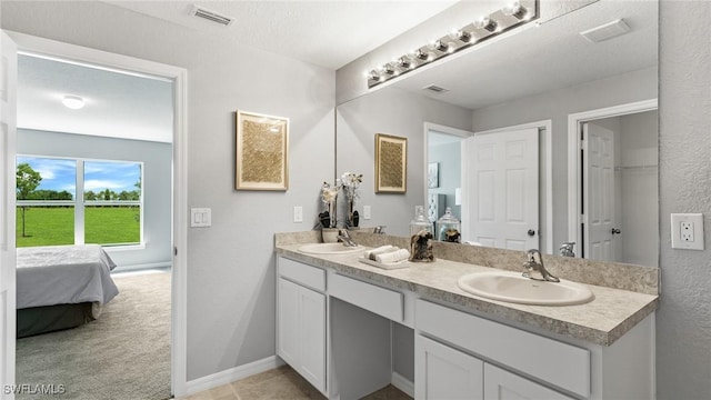 ensuite bathroom featuring visible vents, connected bathroom, a sink, and double vanity