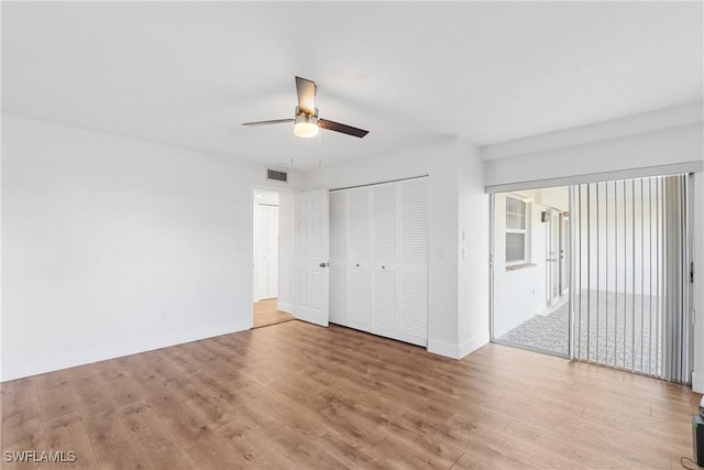 unfurnished bedroom featuring baseboards, visible vents, a ceiling fan, wood finished floors, and a closet