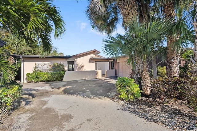 view of front of house featuring driveway, an attached garage, and stucco siding