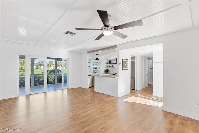 unfurnished living room with visible vents, light wood-style floors, a sink, ceiling fan, and baseboards