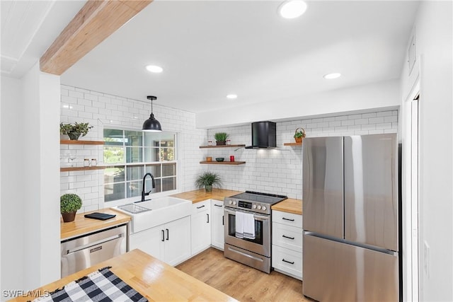 kitchen featuring stainless steel appliances, butcher block counters, a sink, and open shelves